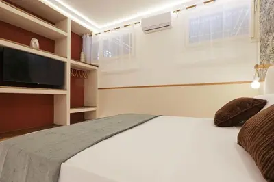 a bedroom with a white bed and a flat screen tv at The Brick Apartment by Nosdom Properties in Rome