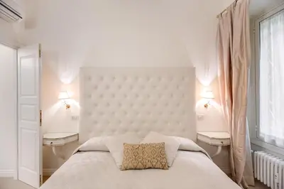 a white bedroom with a large bed and two lamps at Elegant Flat Spanish steps in Rome