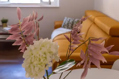 a vase of flowers on a table with a couch at iFlat Bright Brand New 2-Bedroom Apt in Monti in Rome