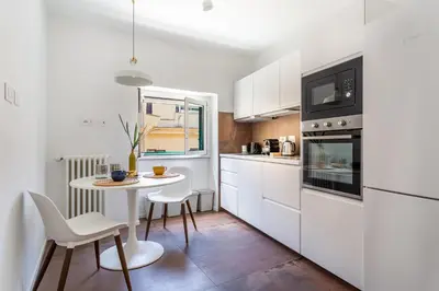 a kitchen with white cabinets and a table and chairs at iFlat Bright Brand New 2-Bedroom Apt in Monti in Rome
