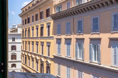 a tall yellow building with blue shutters on it at iFlat Bright Brand New 2-Bedroom Apt in Monti in Rome