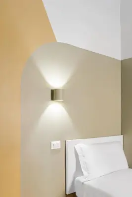 a room with a bed and a light on the wall at Hotel Infinito - Gruppo BLAM HOTELS in Rome