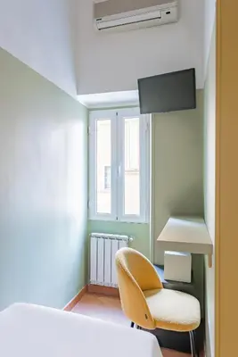 a bedroom with a bed and a chair and a window at Hotel Infinito - Gruppo BLAM HOTELS in Rome