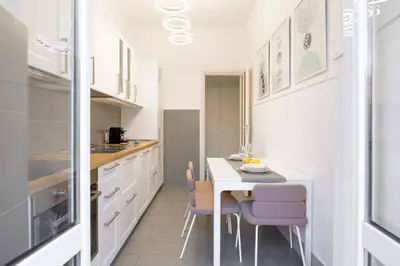 a kitchen with white cabinets and a table and chairs at Piramide Deluxe Apartment in Rome