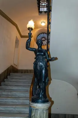 a statue of a woman holding a light next to a staircase at Home at Rome Luxury Navona Suites in Rome