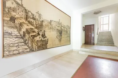 a large painting on a wall in a room with a staircase at House Grimaldi in Rome