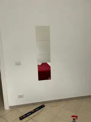 a white wall with a mirror and a weapon on the floor at Peppe's Bed in Rome