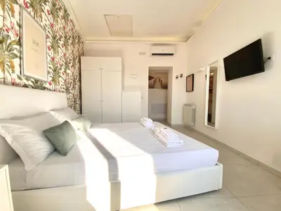 a white bedroom with a white bed and a tv at Prince of Rome Superior Rooms in Rome