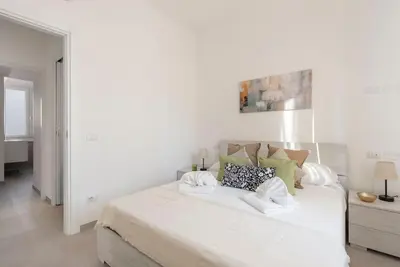 a white bedroom with a large white bed with pillows at Long Bridge Apartment in Rome