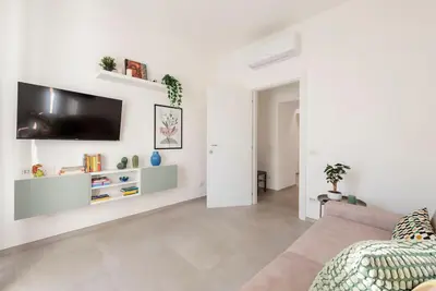 a white living room with a tv on a wall at Long Bridge Apartment in Rome