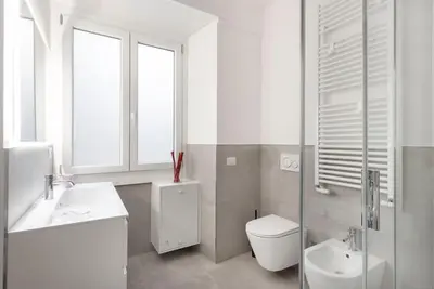 a white bathroom with a toilet and a sink at Long Bridge Apartment in Rome