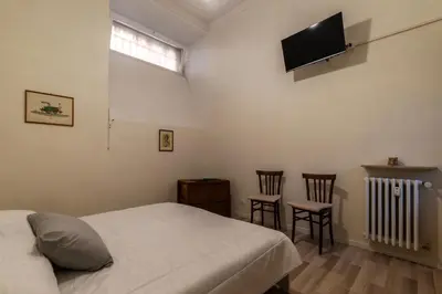 a bedroom with a bed and two chairs and a flat screen tv at GuestHost - Piazza Nievo a Trastevere Cozy Apartment in Rome