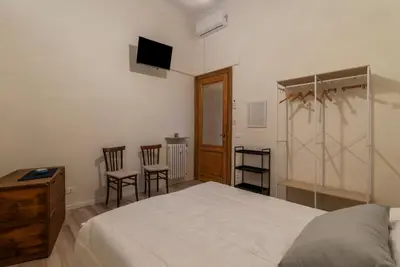 a bedroom with a bed and two chairs and a television at GuestHost - Piazza Nievo a Trastevere Cozy Apartment in Rome