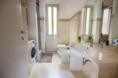 a bathroom with a toilet and a sink and a washing machine at Clodia Vatican House in Rome