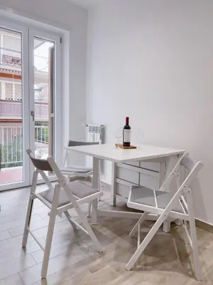 a white table and chairs in a room with a window at Flora's Apartment in Rome