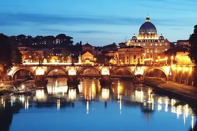 a bridge over a river with a city at night at Velvet Trastevere Apartment in Rome