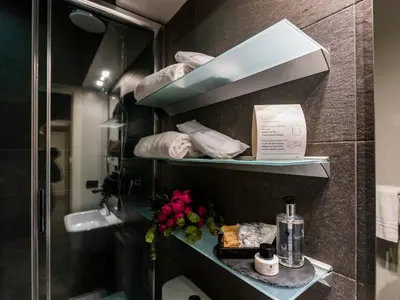 a bathroom with a shower and shelves with towels at JB Relais- Campo de' Fiori in Rome