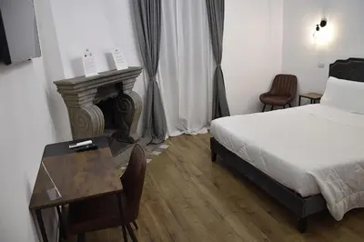 a bedroom with a bed and a desk and a bed and a table and chairs at Roma Chic Cattolica Gemelli in Rome
