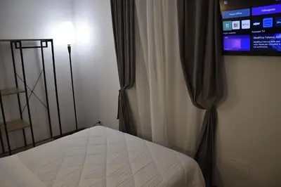 a bedroom with a bed and a curtain and a television at Roma Chic Cattolica Gemelli in Rome