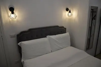 a bed with white sheets and two lights on the wall at Roma Chic Cattolica Gemelli in Rome