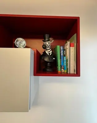 a red shelf with a clock and books on it at Vatican R(h)ome in Rome