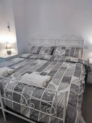 a white bed with a white and black bedspread at Appartamento a San Lorenzo Netsuhe in Rome