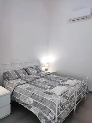 a white bed in a bedroom with a white wall at Appartamento a San Lorenzo Netsuhe in Rome