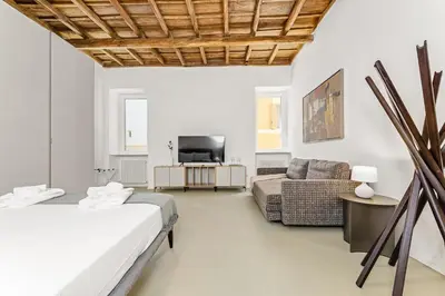 a bedroom with a bed and a couch and a tv at 4BNB - Luxury Navona Apartment in Rome