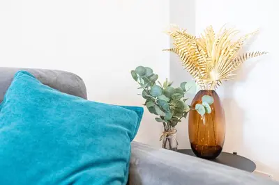 a couch with a blue pillow and a vase with plants at Maisonette Trastevere Wonderful Apartment - Top Collection in Rome