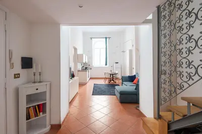 a living room with a blue couch and a kitchen at Vittorio Elegant Two Bedroom Apartment in Rome