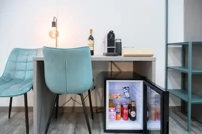 a desk with a blue chair and a refrigerator at Trastevere Luxury Rooms in Rome
