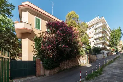 a building with a bush with purple flowers on a street at GuestHost - Sant'Agnese & Nomentana Cozy Apartment in Rome