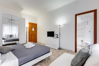 a white bedroom with a bed and a mirror at DAMA PROPERTY - Trastevere Homestay in Rome