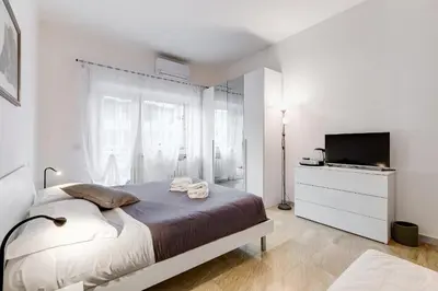 a white bedroom with a bed and a television at DAMA PROPERTY - Trastevere Homestay in Rome