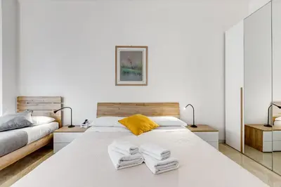 a white bedroom with two beds and two lamps at DAMA PROPERTY - Trastevere Homestay in Rome
