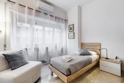 a white bedroom with two beds and a window at DAMA PROPERTY - Trastevere Homestay in Rome
