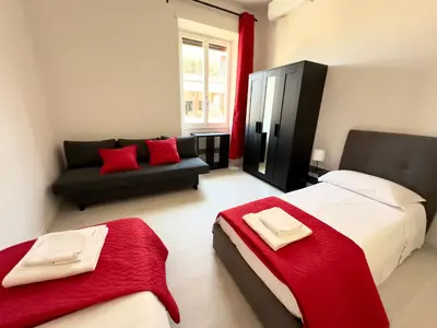 a bedroom with a bed and a couch with red pillows at St Pietro city center near subway in Rome