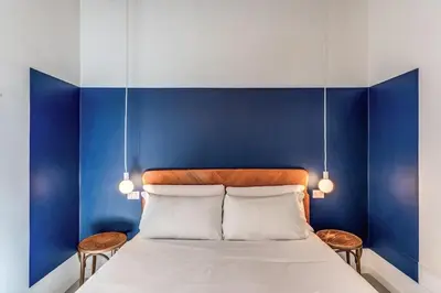 a bedroom with blue walls and a bed with two chairs at Trastevere Vicolo del Leopardo suite in Rome