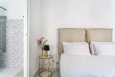 a bedroom with a white bed with a gold side table at iFlat Cozy and Elegant apt near Spanish Steps in Rome