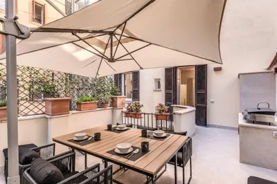 a patio with a table and chairs and an umbrella at 3 bedroom apartment Via Genova Monti area in Rome