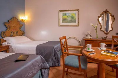 a room with two beds and a table and a desk at Hotel Mozart in Rome