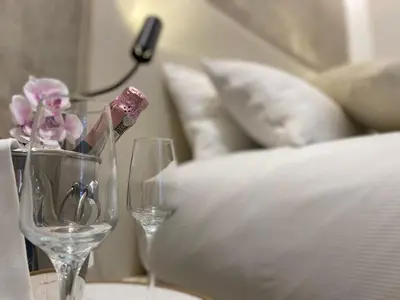 two wine glasses on a table next to a bed at Suite Croce in Rome