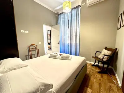 a bedroom with a large white bed and a chair at Cheerful flat in funky Rome in Rome