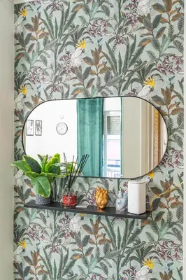 a bathroom mirror on a wall with floral wallpaper at Domus Farnesina Ponte Milvio in Rome