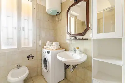 a bathroom with a sink and a washing machine at Green Holiday Penthouse in Rome