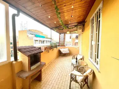 an outdoor patio with a stove and chairs on a building at Green Holiday Penthouse in Rome