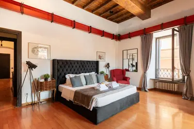 a bedroom with a large bed and a red chair at Appartamento con vista piazza Navona in Rome