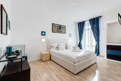 a white bedroom with a white bed and blue curtains at Ripetta Central Suites in Rome