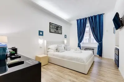 a bedroom with a white bed and blue curtains at Ripetta Central Suites in Rome