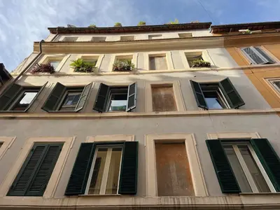 a tall building with green shuttered windows and plants at Campo dei fiori Suite in Rome